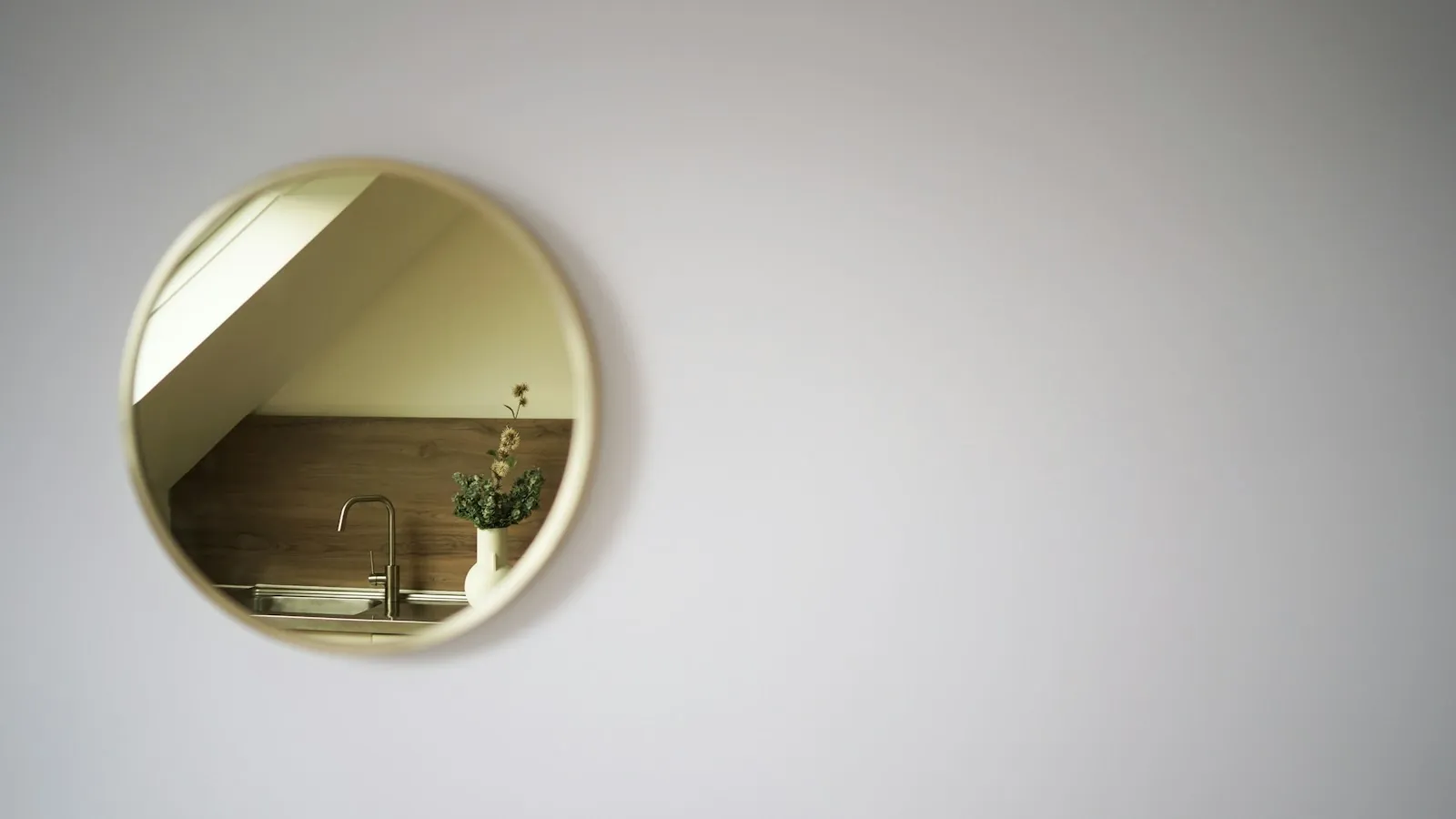 A round mirror hanging on a wall above a sink